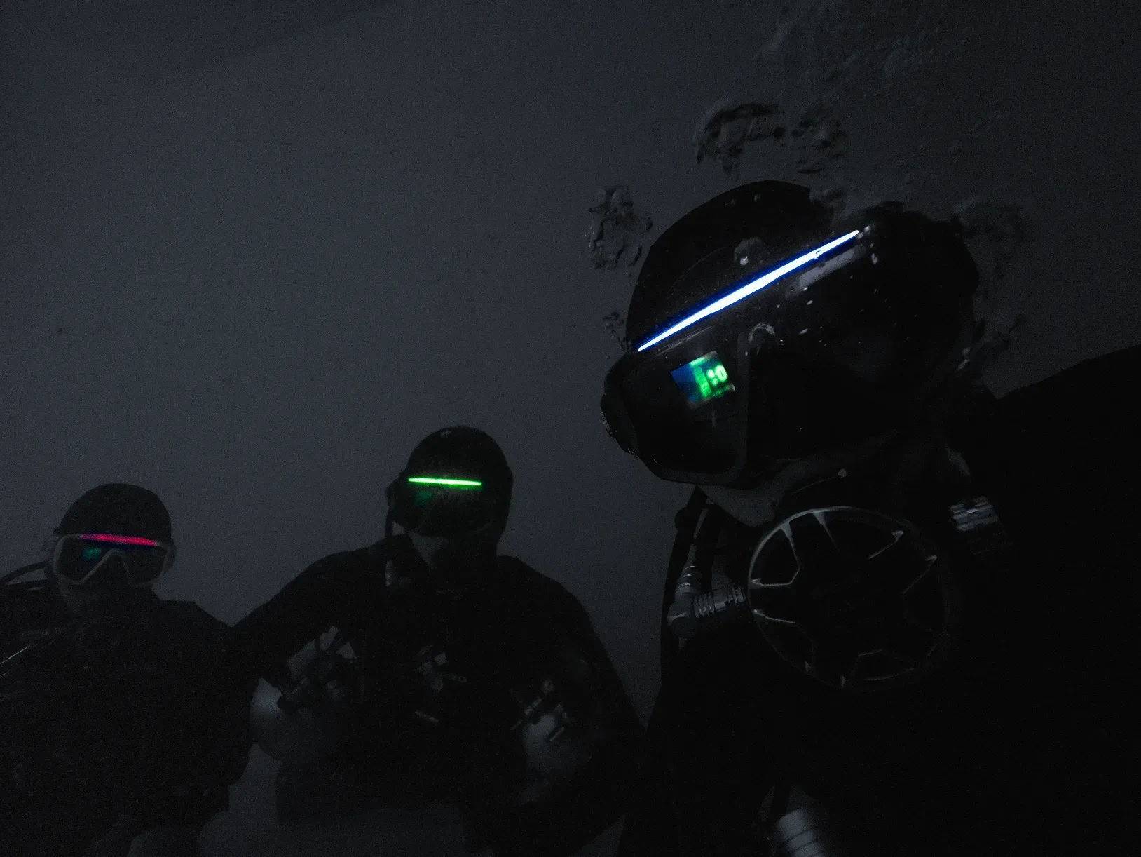 Three divers wearing masks illuminated by custom RGB light strips